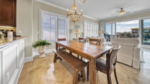 A spacious kitchen with a wooden dining table, a chandelier, and a view of the outdoors.