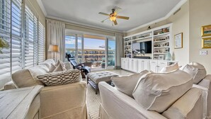 A spacious living room with a large sofa set, a flat-screen TV, and a ceiling fan.