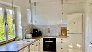 Una cocina moderna con armarios blancos, lavavajillas negro y encimera de madera.