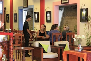 A restaurant interior with wooden furniture, tables, and chairs, and a person standing near the entrance.