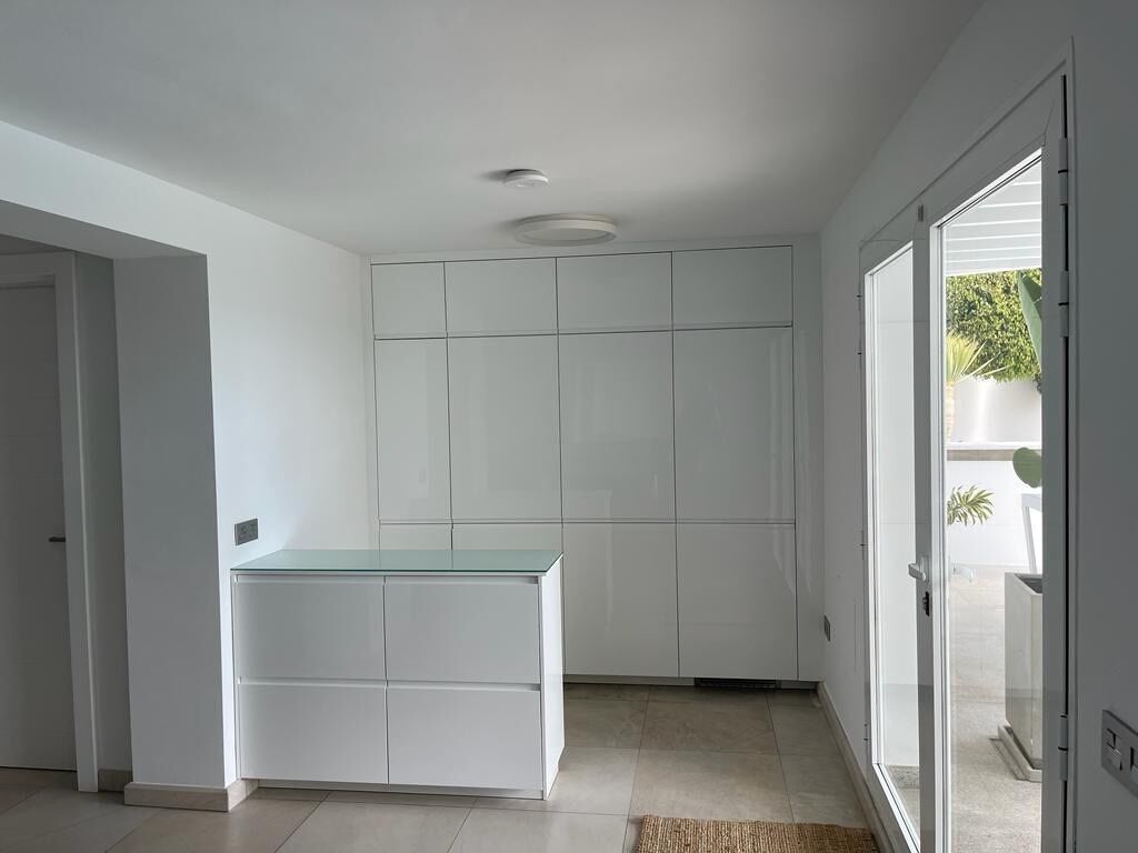 A modern kitchen with white cabinetry and a glass countertop.