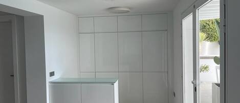 A modern kitchen with white cabinetry and a glass countertop.