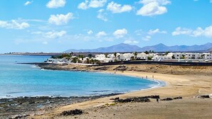 A coastal town with white buildings, a beach, and mountains in the background. - Villa del Mar - Beachhouse (Playa Honda)