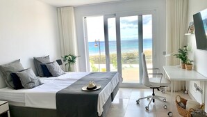 A modern hotel room with a bed, a desk, and a view of the beach. - Villa del Mar - Beachhouse (Playa Honda)