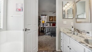 A modern bathroom with a large mirror, a bathtub, and a vanity with a marble countertop. - Beautiful n Cozy - Great Location - Private Heated Pool (Chandler)