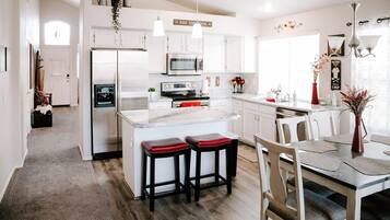 A modern kitchen with white cabinetry, stainless steel appliances, and a central island with stools.