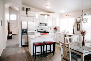 A modern kitchen with white cabinetry, stainless steel appliances, and a central island with stools. - Beautiful n Cozy - Great Location - Private Heated Pool (Chandler)