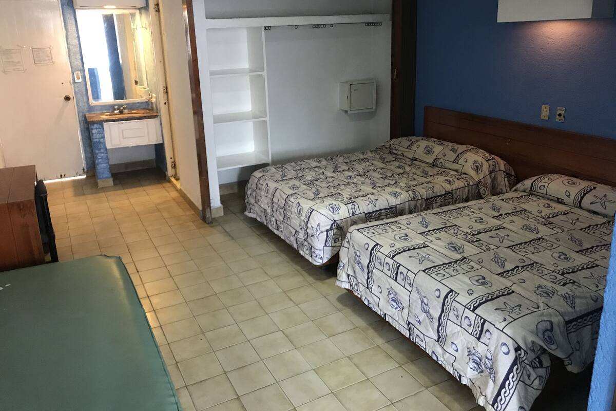 Una habitación con dos camas, una mesita y un armario.