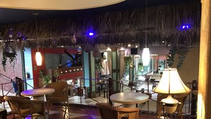 Un restaurante con piso a cuadros, muebles de mimbre y plantas colgantes.