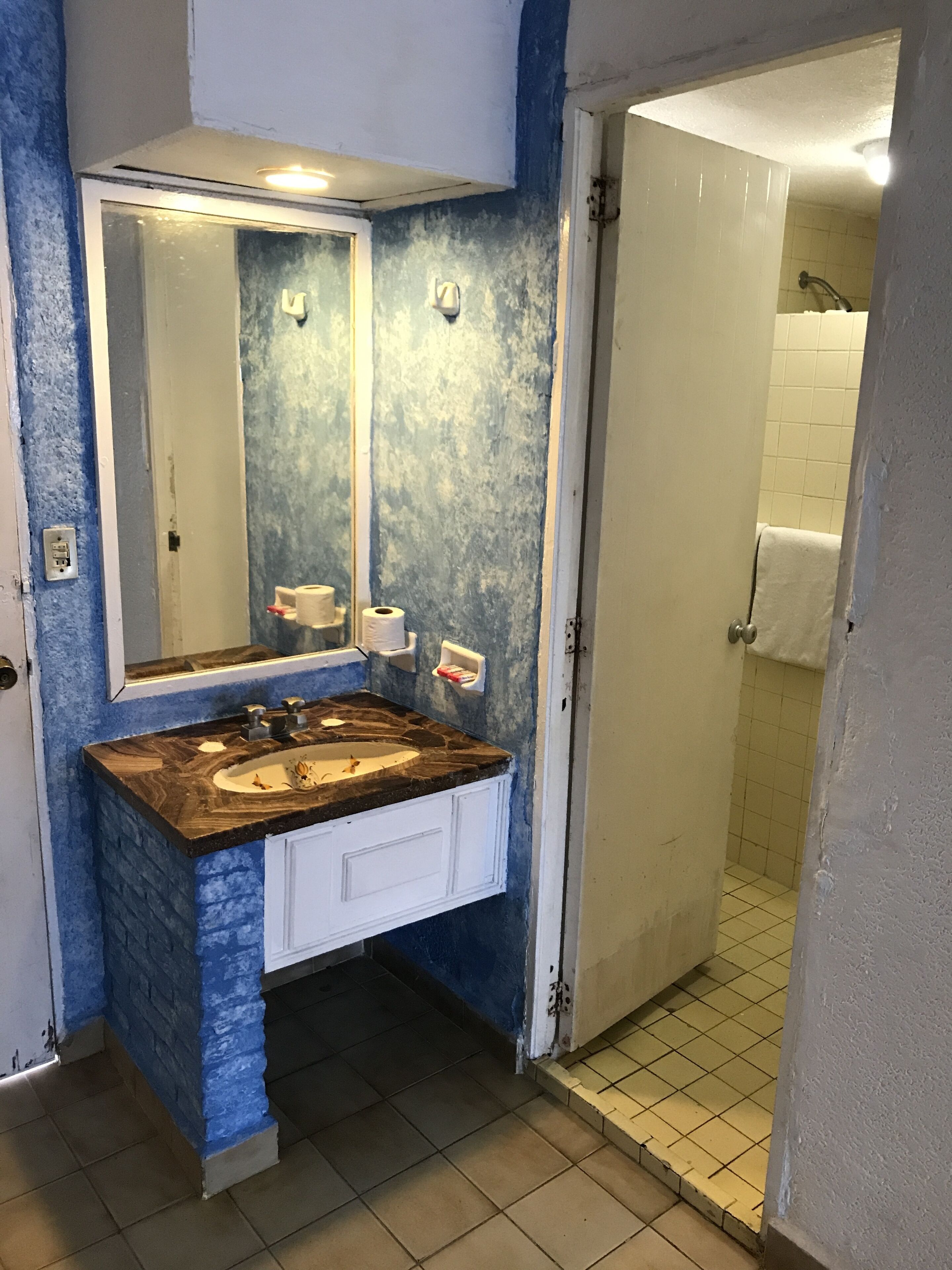 Un baño con lavamanos doble, un espejo grande y zona de ducha.