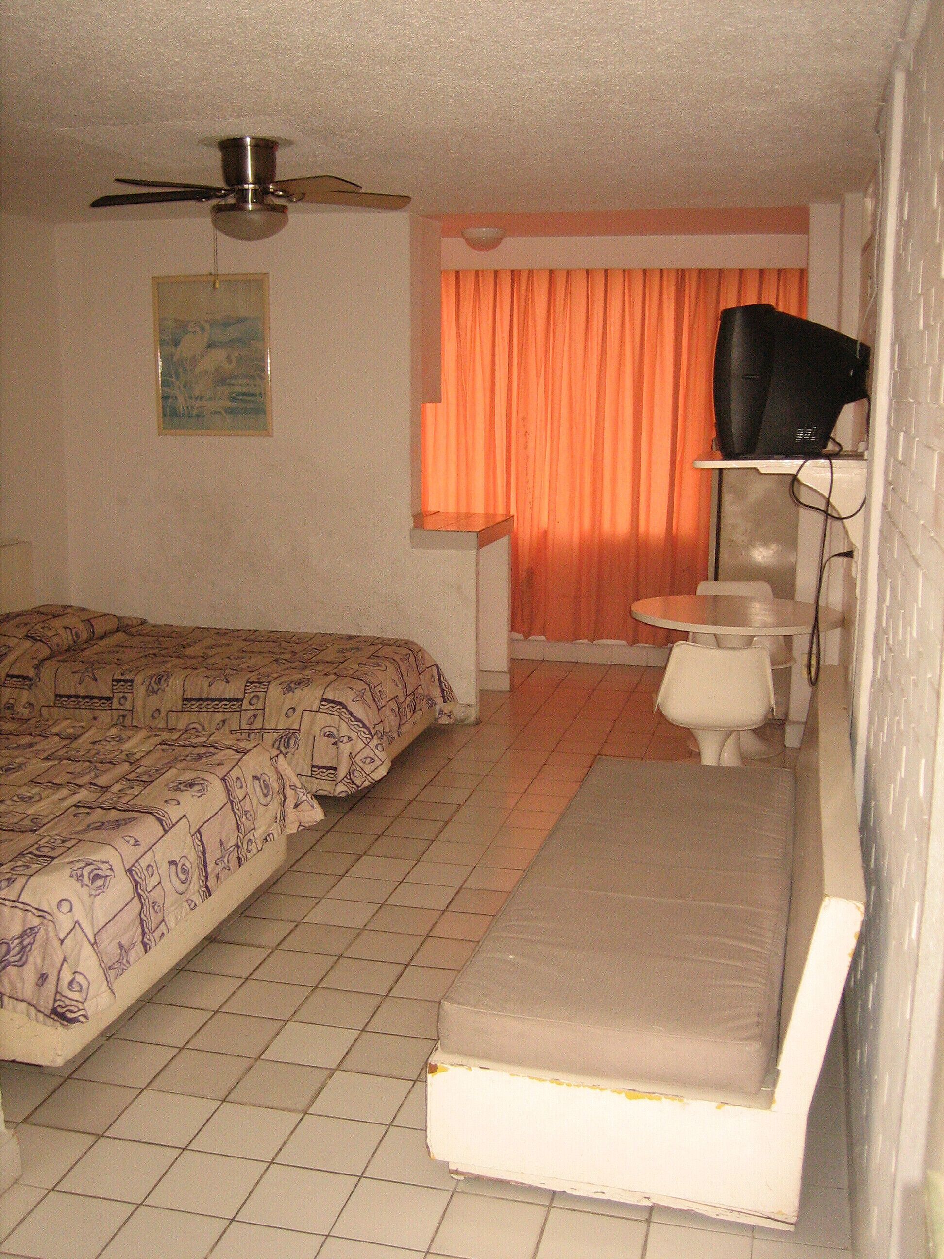 A small, compact room with a bed, a desk, and a television.