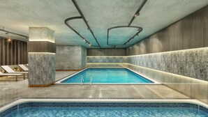 Een modern binnenzwembad met een heldere blauwe waterattractie, omringd door betonnen muren en een houten vloer.