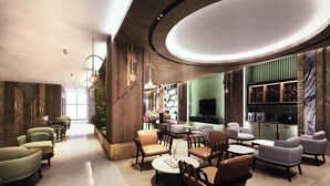Een moderne lobby met zithoeken, een televisie en een groene wand met een boekenkast.