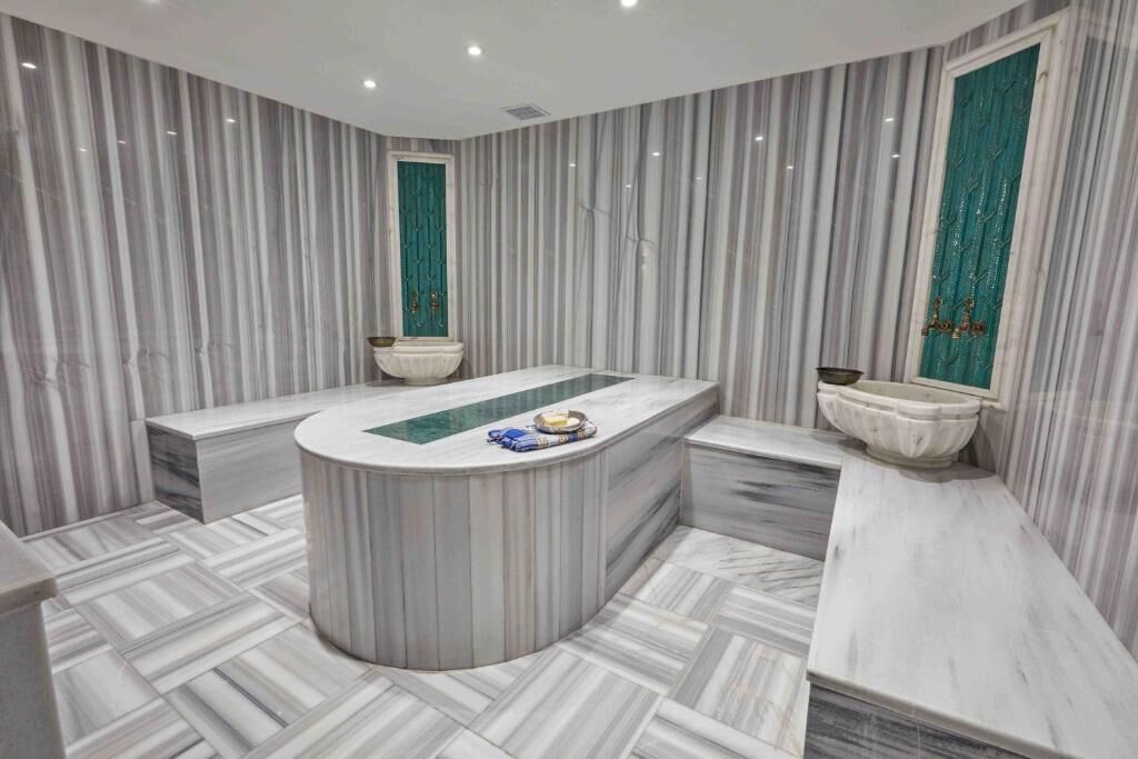 Un baño moderno con una bañera independiente, paredes de mármol y un patrón de suelo tipo espiga.