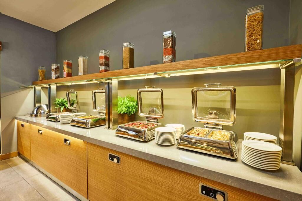 A buffet setup with various food containers and serving utensils.