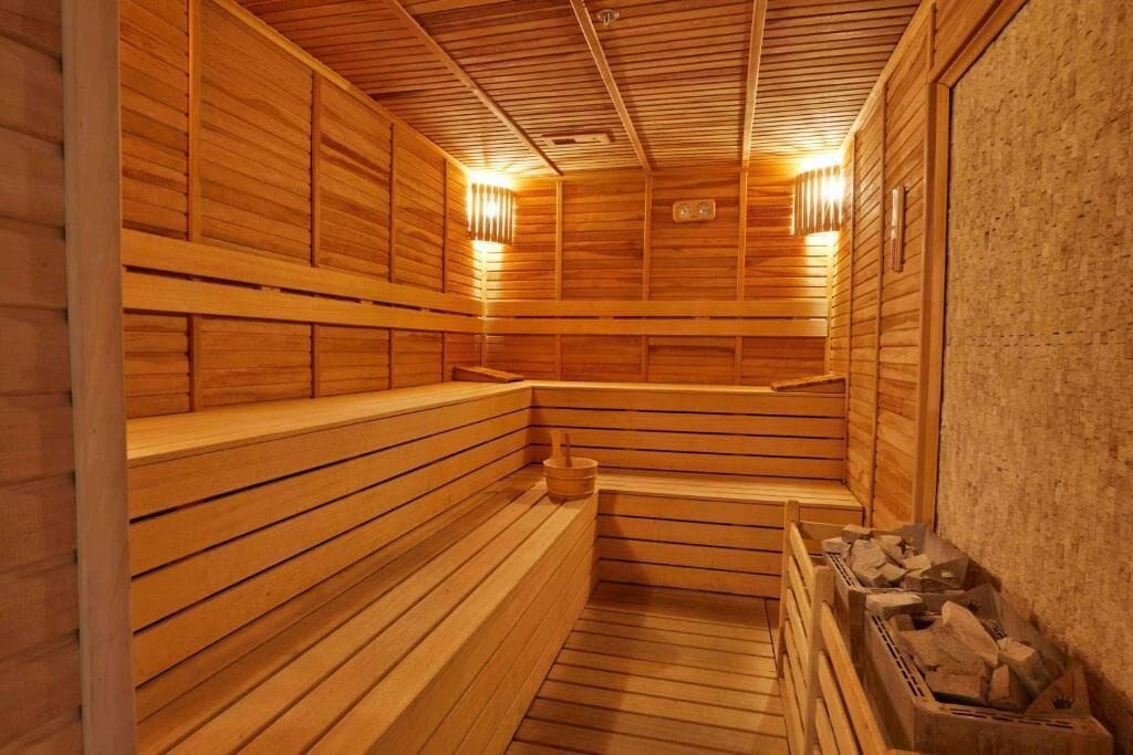 Una sauna con panche in legno e una parete in pietra.