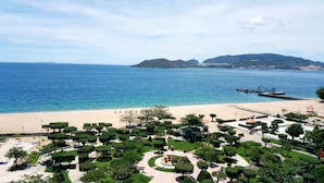 Une station balnéaire dotée d’une plage de sable, de jardins bien entretenus et offrant une vue sur la mer et les montagnes lointaines.