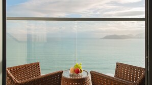 A balcony with wicker chairs and a table with fruit. - Grand Gosia Hotel (Nha Trang)