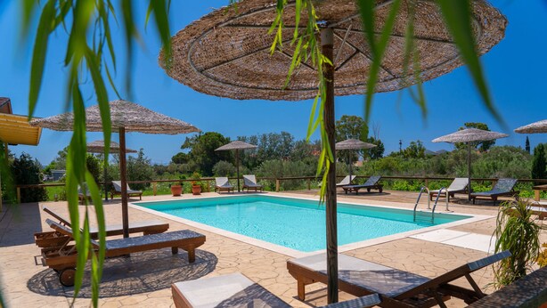 Un área de piscina con sillones de descanso y sombrillas.