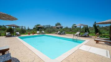Una piscina al aire libre de temporada, sombrillas