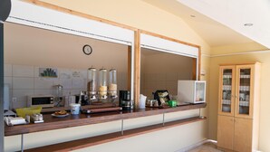Una cocina con encimera de madera, microondas, cafetera y un armario con puertas de vidrio.