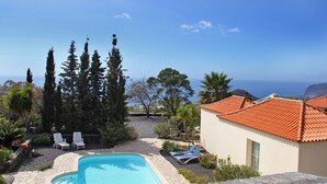 A pool area with lounge chairs, a small building with a tiled roof, and a view of the sea. - Casa de las Estrellas (Los Llanos)