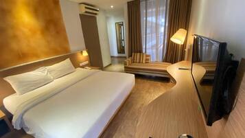 Habitación de hotel con una cama grande, un sofá, un televisor y un equipo de aire acondicionado.