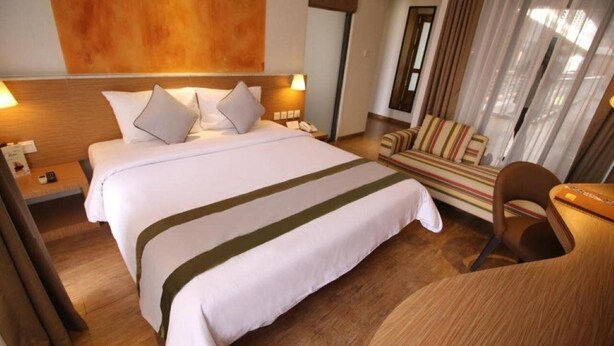 A hotel room with a large bed, a desk, a chair, and a sofa.
