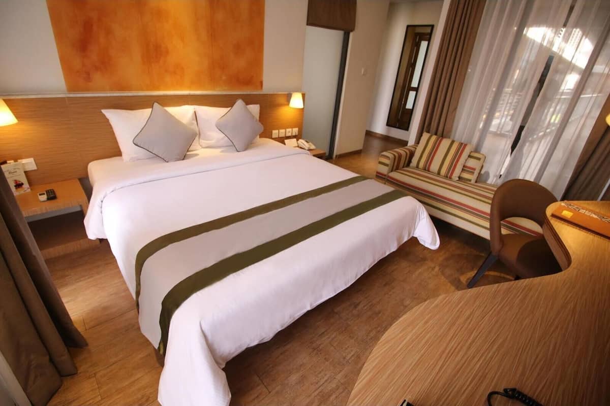 Een hotelkamer met een groot bed, een bureau, een stoel en een bank.