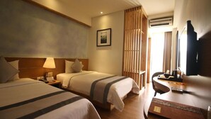 A hotel room with two beds, a desk, a chair, a TV, and a picture on the wall.