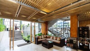A modern lobby with a wooden ceiling, a sofa, a coffee table, and a staircase.