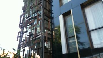 Un edificio moderno con fachada de vidrio reflectante y una serie de elementos verticales de madera.