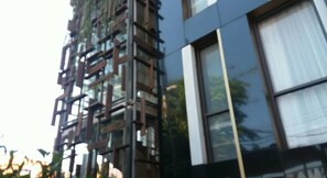 A modern building with a reflective glass facade and a series of vertical wooden elements. - Liberta Hotel Jimbaran (Kedonganan)
