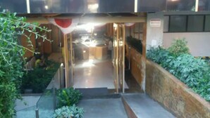 A hotel entrance with a glass door, a staircase leading inside, and a small garden area with plants. - Liberta Hotel Jimbaran (Kedonganan)