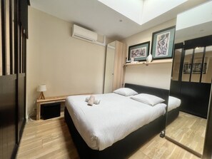Een hotelkamer met een bed, een nachtkastje met een lamp, een kledingkast en een spiegel.