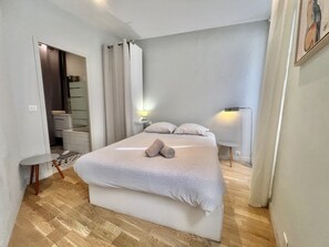 A bedroom with a bed, a bedside table, a lamp, and a view of a bathroom. - Jaures 2 bedrooms 7 minuts walking from Palais (Cannes)