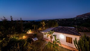 Una casa con techo de tejas, rodeada de vegetación y vistas al mar.