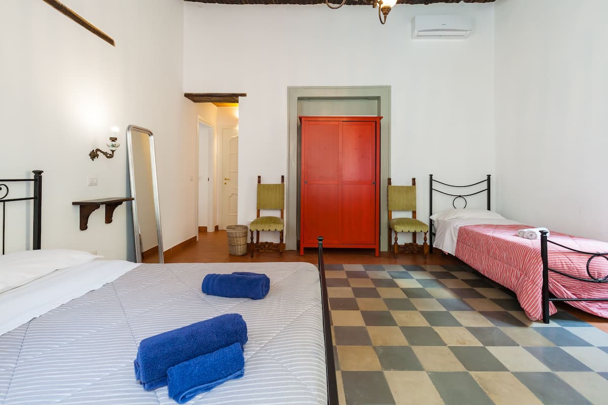 A hotel room with two beds, a red door, a checkered floor, and a mirror on the wall.