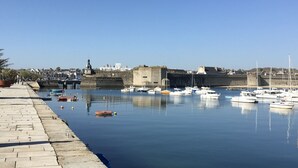 A harbor with boats docked, a stone wall, and a clear sky. - Joli Studio Avec Grand Balcon vue mer (Concarneau)