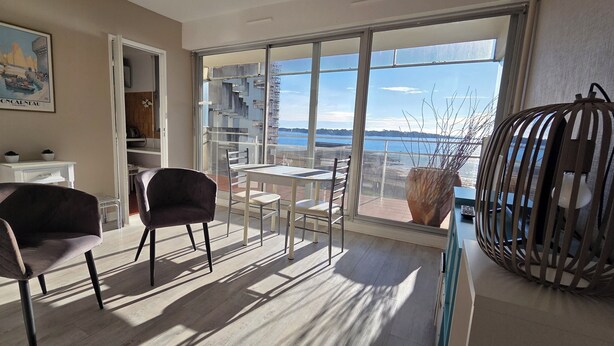 A balcony with a view of the sea, a chair, a table, and a decorative birdcage. - Joli Studio Avec Grand Balcon vue mer (Concarneau)