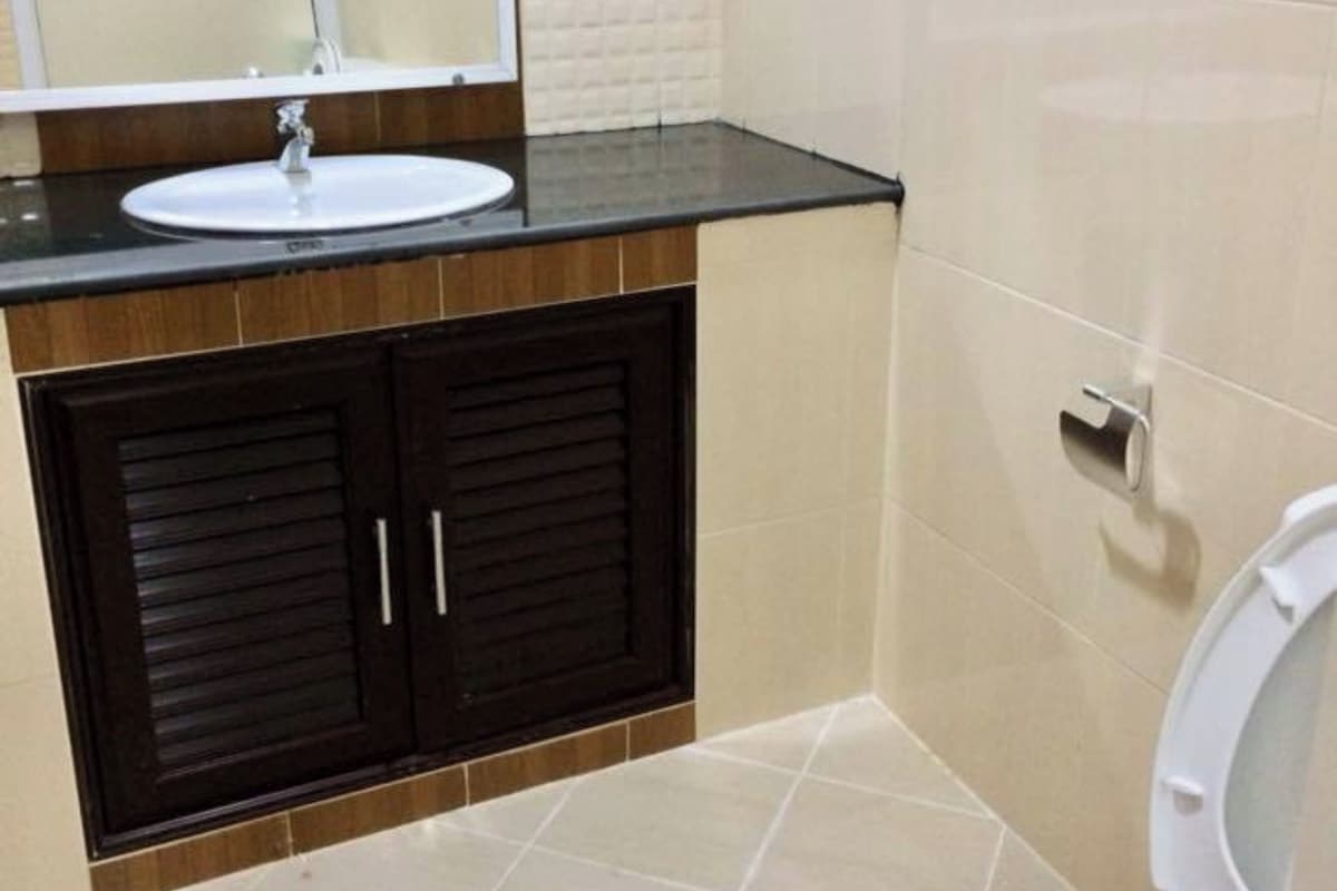 Ein Badezimmer mit einem weißen Waschbecken, dunklen Schränken und einer Toilette.