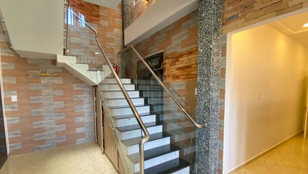 Una escalera moderna con barandillas de vidrio y una pared de acento de piedra.