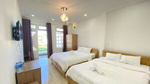 Habitación de hotel con dos camas, un armario de madera, un escritorio con silla y un televisor en la pared.