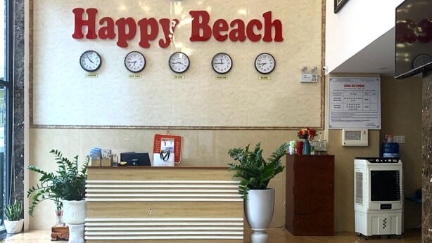 A reception desk with a 'Happy Beach' sign, clocks indicating different time zones, a calendar, and a water dispenser.