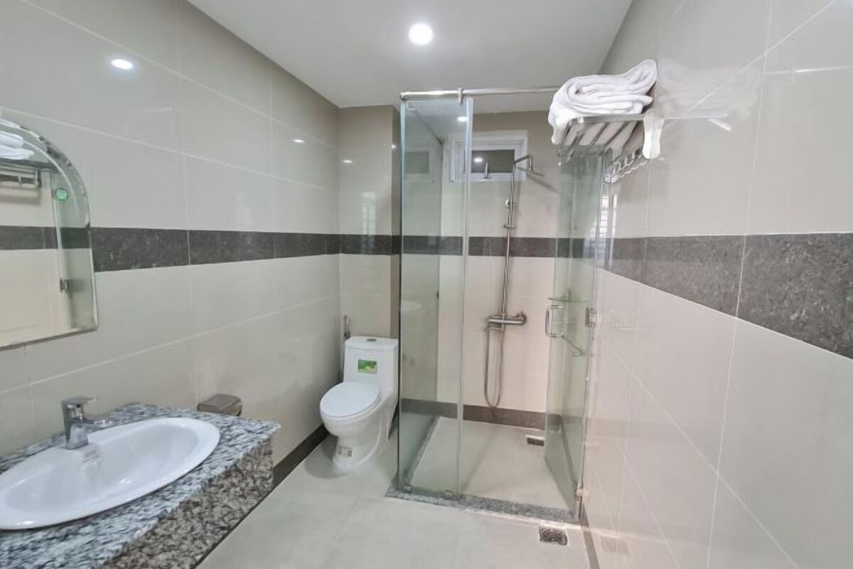 Ein modernes Badezimmer mit einer Duschkabine aus Glas, einem Waschbecken mit Granitplatte und einer Toilette.