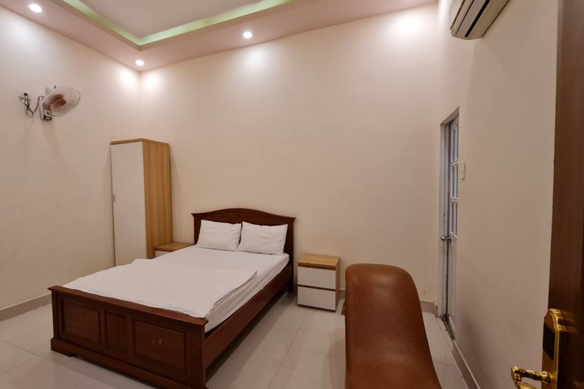A bedroom with a wooden bed, a nightstand, a wardrobe, and a bench.