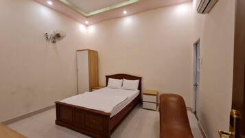 A bedroom with a wooden bed, a nightstand, a wardrobe, and a bench.