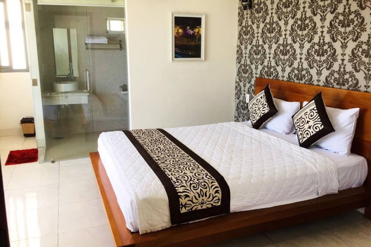 Habitación de hotel con una cama grande, zona de ducha y un papel tapiz estampado.