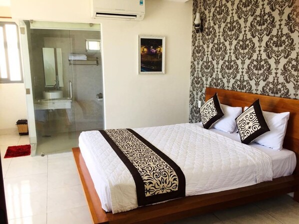 A hotel room with a large bed, a shower area, and a patterned wallpaper. - Hanatel Hotel (Bac Nha Trang)