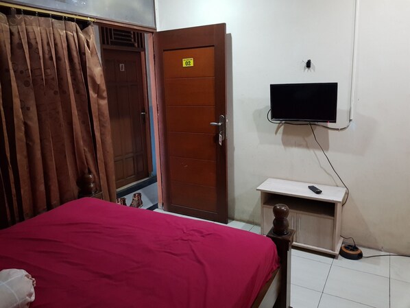 A room with a bed, a TV mounted on the wall, a wooden door, and a curtain. - Hotel Alifah 1 Syariah (Tangerang)